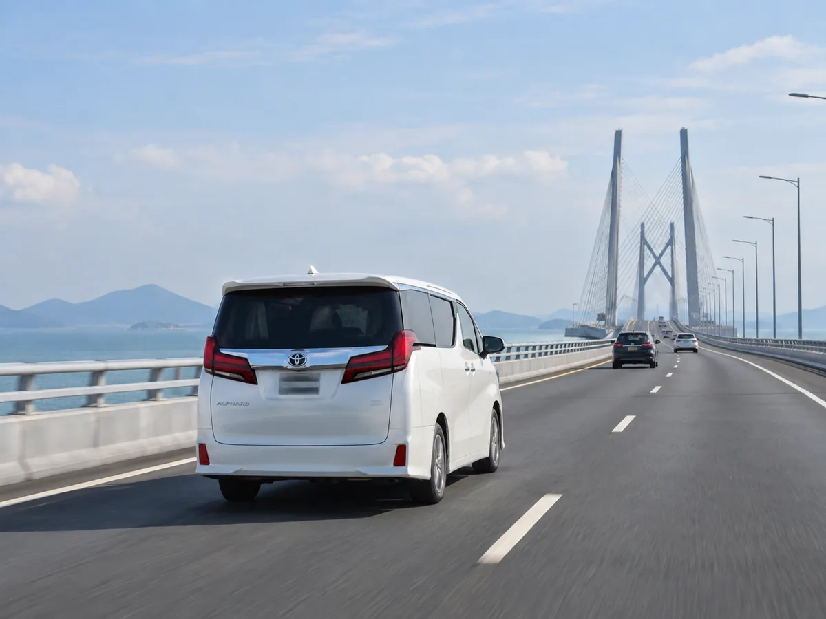 Alphard travelling on a coastal bridge