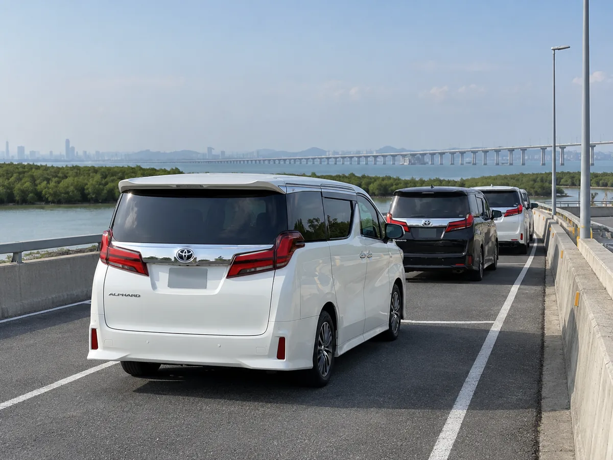 Three Toyota Alphard MPVs travelling along an elevated road beside the water